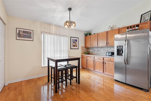 9 Pittman Dr, Palm Coast, FL 32164 - kitchen featuring light wood finished floors, a textured ceiling, tasteful backsplash, stainless steel refrigerator with ice dispenser, and light countertops