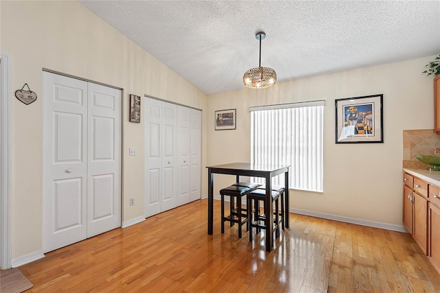 9 Pittman Dr, Palm Coast, FL 32164 - dining area featuring a textured ceiling, light wood-type flooring, baseboards, an inviting chandelier, and lofted ceiling