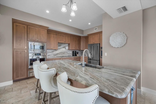 2590 Palm Ave, Flagler Beach, FL 32136 - kitchen featuring stainless steel appliances, a breakfast bar area, brown cabinetry, backsplash, and recessed lighting