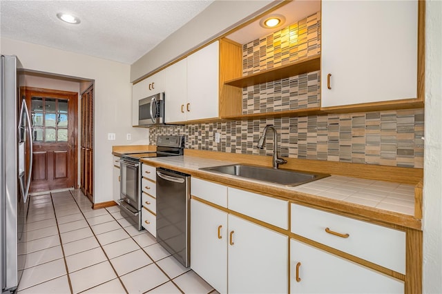 200 Florida Shores Blvd, Daytona Beach, FL 32118 - kitchen with open shelves, backsplash, a sink, appliances with stainless steel finishes, and white cabinetry