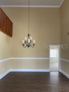 5 Nantucket Dr, Palm Coast, FL 32137 - unfurnished room with dark wood finished floors, an inviting chandelier, ornamental molding, and baseboards