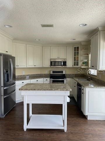5 Nantucket Dr, Palm Coast, FL 32137 - kitchen featuring stainless steel appliances, a center island, a sink, a textured ceiling, and dark wood-style flooring