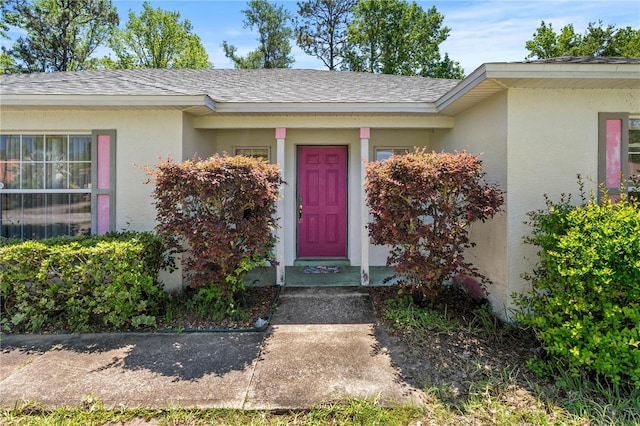 property entrance featuring stucco siding and roof with shingles