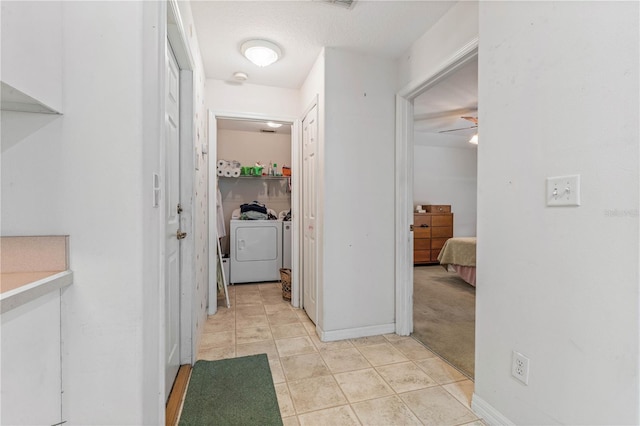 hall featuring independent washer and dryer, baseboards, and light tile patterned floors