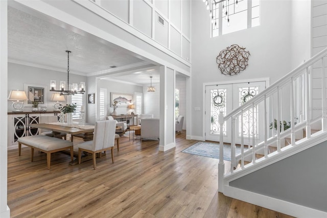 28 Cinnamon Grove Ln, Palm Coast, FL 32137 - foyer entrance with a healthy amount of sunlight, crown molding, light wood-style flooring, and a notable chandelier