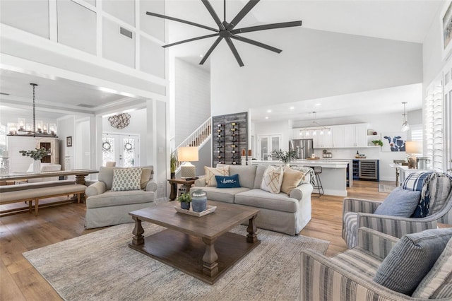 28 Cinnamon Grove Ln, Palm Coast, FL 32137 - living room featuring light wood-style flooring, a high ceiling, a wealth of natural light, and ceiling fan with notable chandelier