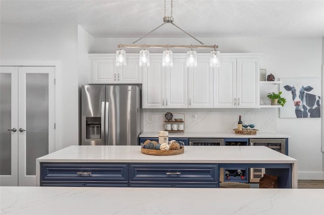 28 Cinnamon Grove Ln, Palm Coast, FL 32137 - kitchen featuring stainless steel refrigerator with ice dispenser, blue cabinets, and white cabinetry