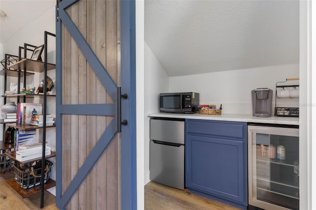 28 Cinnamon Grove Ln, Palm Coast, FL 32137 - bar featuring freestanding refrigerator, beverage cooler, a textured ceiling, and light wood-style floors