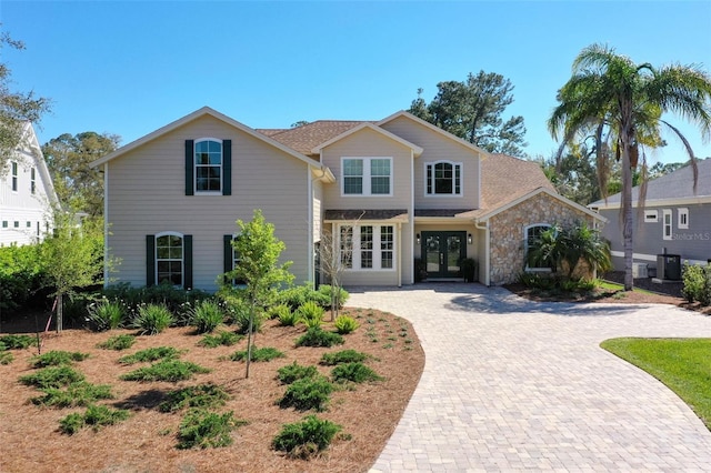28 Cinnamon Grove Ln, Palm Coast, FL 32137 - traditional-style home featuring central AC, driveway, french doors, and stone siding
