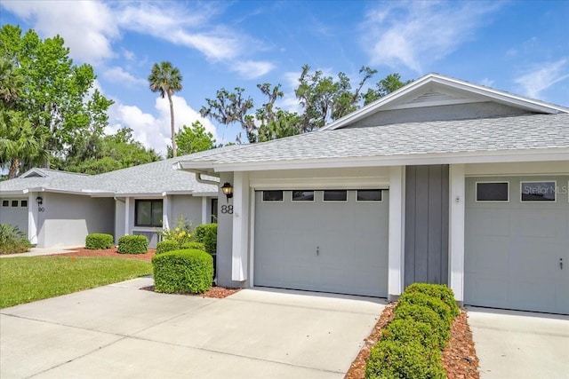 single story home featuring roof with shingles, concrete driveway, an attached garage, and board and batten siding