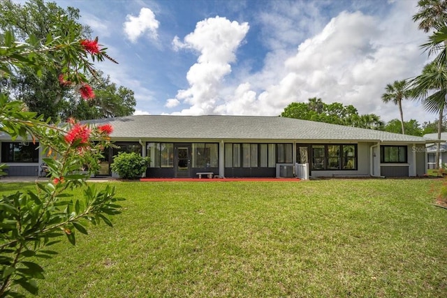 back of house featuring a sunroom, central air condition unit, a yard, and a shingled roof
