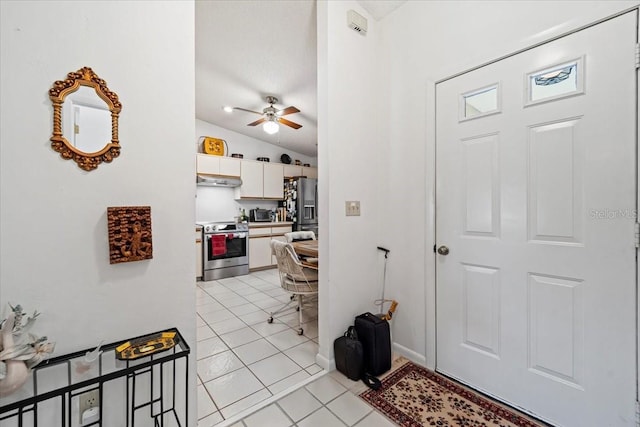 foyer entrance with lofted ceiling, light tile patterned floors, ceiling fan, and baseboards