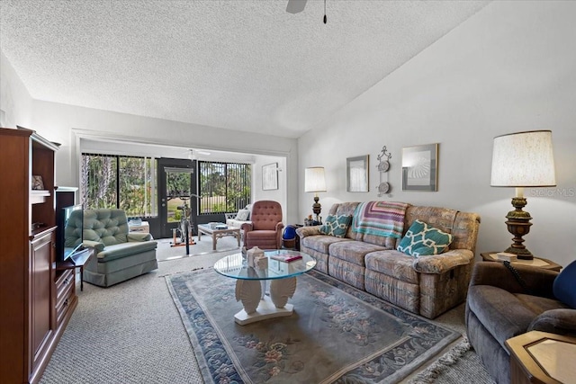 living area featuring carpet, a ceiling fan, vaulted ceiling, and a textured ceiling