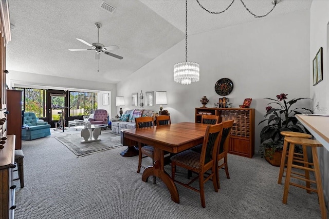 carpeted dining area featuring a textured ceiling, visible vents, vaulted ceiling, and ceiling fan with notable chandelier