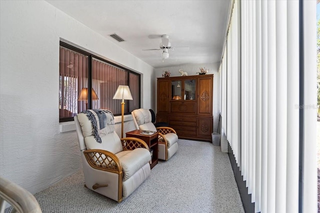 living area featuring visible vents, ceiling fan, and carpet