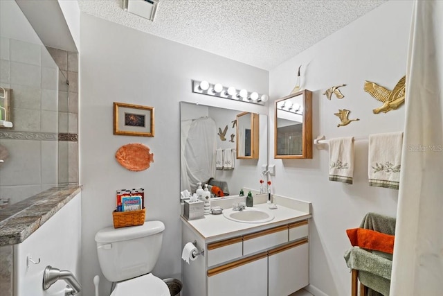 full bathroom featuring toilet, a tile shower, a textured ceiling, and vanity