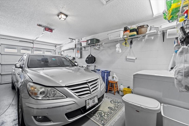 garage featuring concrete block wall, a garage door opener, and washer and clothes dryer