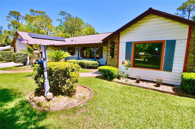view of front facade featuring solar panels and a front yard