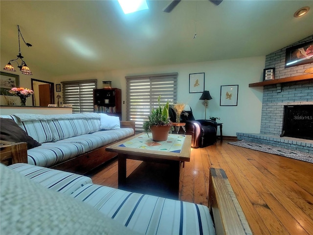 living room featuring ceiling fan, a brick fireplace, and hardwood / wood-style floors