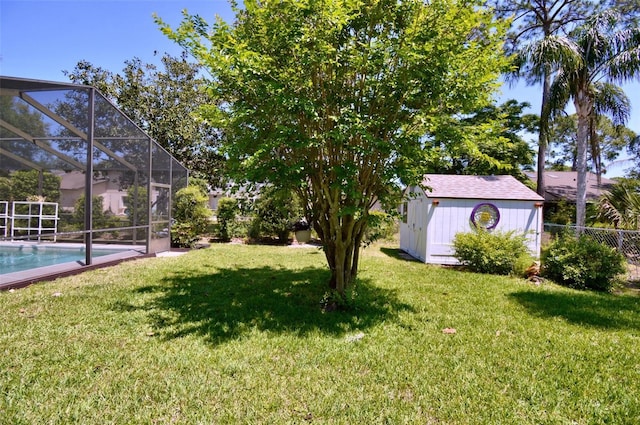view of yard featuring fence, an outdoor pool, a lanai, a shed, and an outbuilding