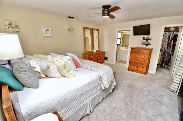 bedroom with a closet, visible vents, light carpet, a spacious closet, and connected bathroom