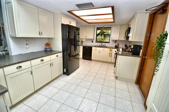 kitchen featuring a sink, black appliances, visible vents, decorative backsplash, and light tile patterned floors