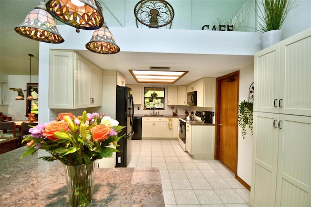 kitchen featuring a sink, dark stone counters, light tile patterned flooring, black appliances, and visible vents