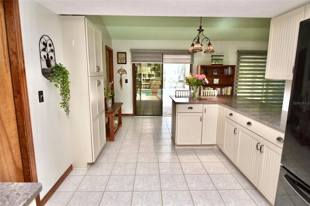 kitchen featuring decorative light fixtures, light tile patterned flooring, black fridge, a peninsula, and a chandelier