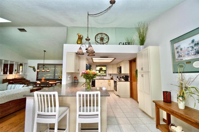 kitchen with a peninsula, a kitchen breakfast bar, an inviting chandelier, open floor plan, and electric stove