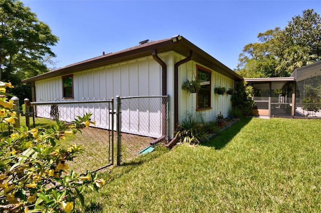 view of home's exterior with a yard, a sunroom, fence, and a gate