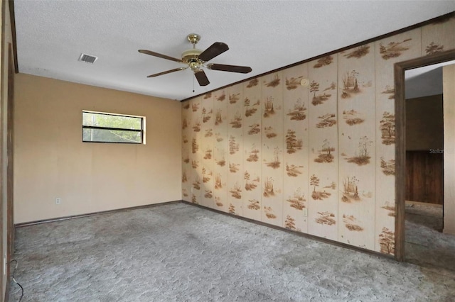 carpeted spare room with a textured ceiling, visible vents, a ceiling fan, and baseboards