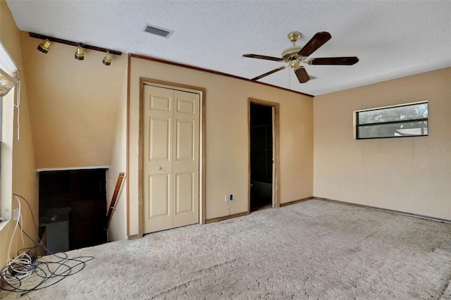 unfurnished bedroom with visible vents, carpet floors, a closet, a textured ceiling, and ceiling fan