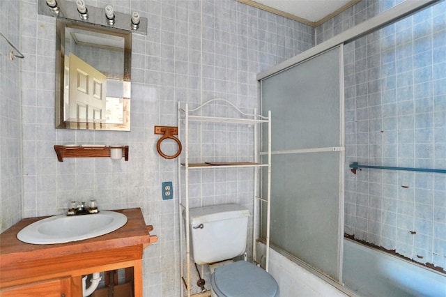 full bath with tile walls, vanity, enclosed tub / shower combo, and toilet
