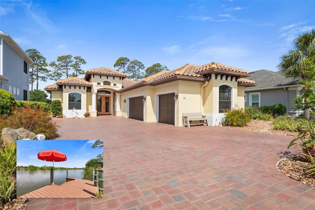 mediterranean / spanish-style house with a tiled roof, an attached garage, french doors, and stucco siding