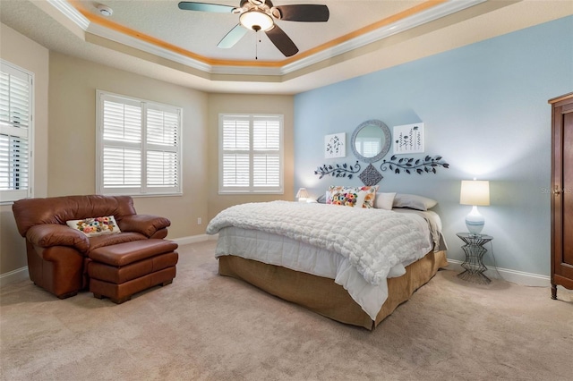 bedroom featuring baseboards, light carpet, crown molding, and a tray ceiling