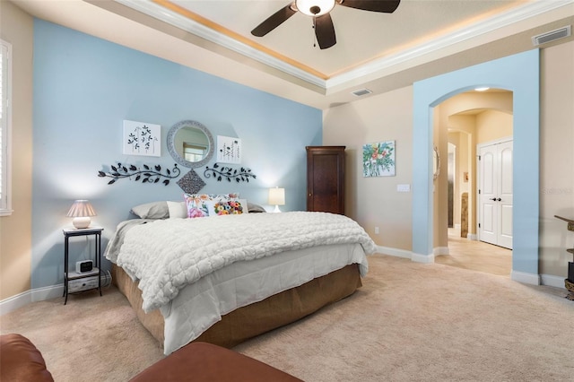 bedroom featuring arched walkways, visible vents, light colored carpet, and a tray ceiling