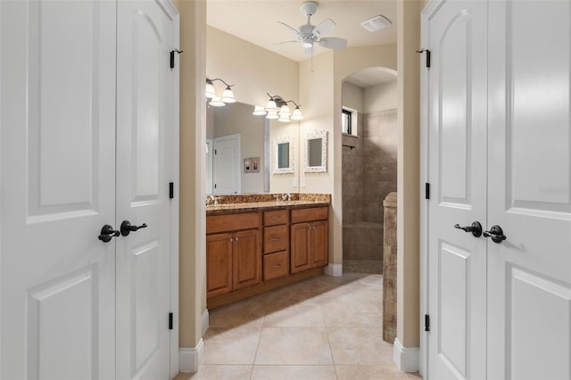 full bathroom with a sink, double vanity, ceiling fan, tile patterned floors, and a walk in shower