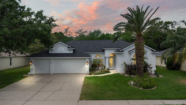 single story home with concrete driveway, a shingled roof, stucco siding, a yard, and a garage