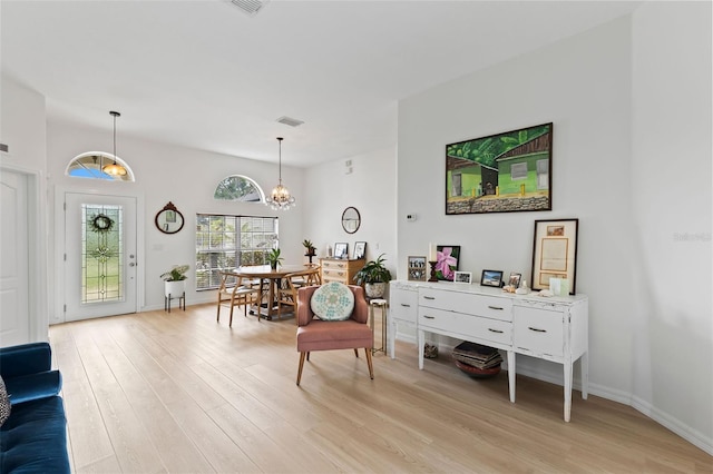 sitting room featuring visible vents, light wood-type flooring, an inviting chandelier, and baseboards