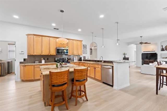 kitchen featuring open floor plan, appliances with stainless steel finishes, a peninsula, and a sink
