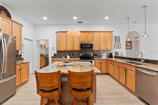 kitchen with light stone countertops, a sink, stainless steel appliances, and decorative backsplash