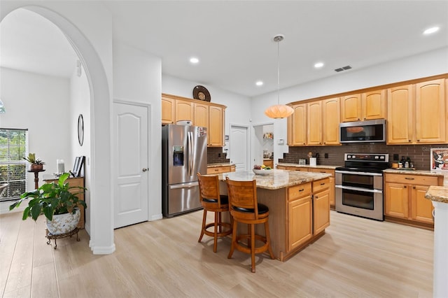 kitchen with visible vents, stainless steel appliances, a kitchen island, and light wood finished floors