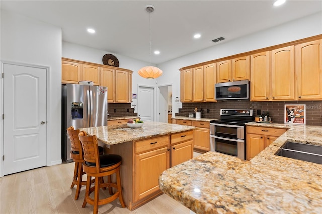 kitchen featuring a center island, light stone countertops, stainless steel appliances, and decorative backsplash