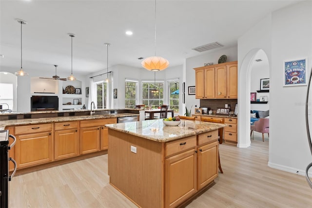 kitchen featuring a center island, visible vents, light wood-style flooring, and arched walkways