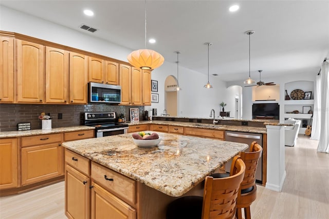 kitchen with light stone counters, appliances with stainless steel finishes, a center island, visible vents, and a peninsula