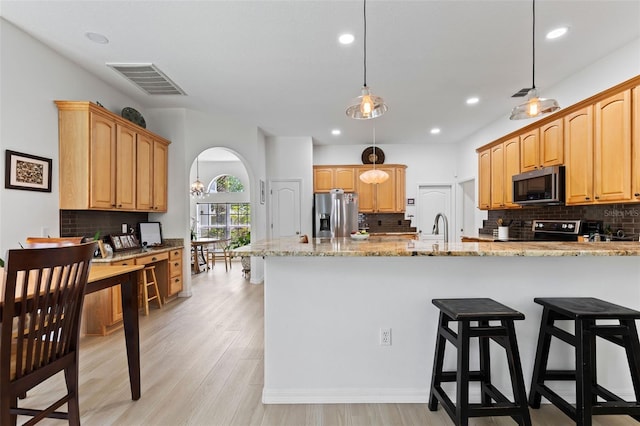 kitchen featuring light stone countertops, a breakfast bar, visible vents, backsplash, and appliances with stainless steel finishes