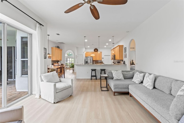 living room with light wood finished floors, recessed lighting, ceiling fan, and arched walkways