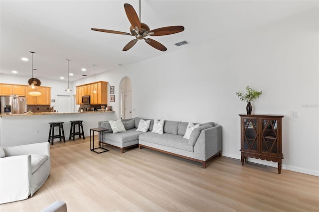 living room featuring recessed lighting, ceiling fan, light wood-type flooring, visible vents, and arched walkways