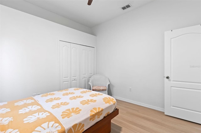 bedroom featuring light wood-style floors, a closet, ceiling fan, baseboards, and visible vents