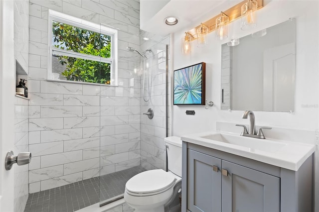 full bathroom with toilet, a tile shower, and vanity